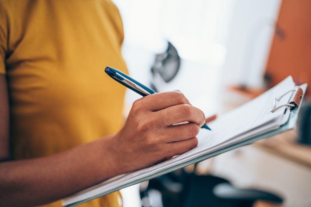 Cropped shot of an unrecognizable businesswoman making notes on a clipboard.