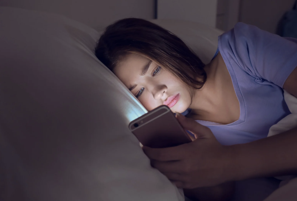 A woman looking at her phone in bed.